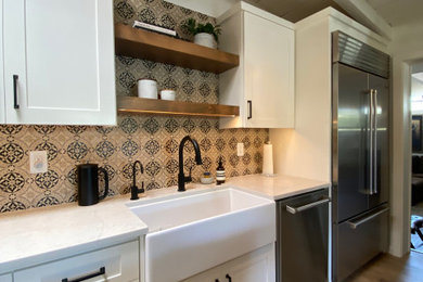 Example of a mid-sized country galley vinyl floor, beige floor and exposed beam eat-in kitchen design in Phoenix with a farmhouse sink, flat-panel cabinets, white cabinets, quartz countertops, beige backsplash, ceramic backsplash, stainless steel appliances, two islands and white countertops