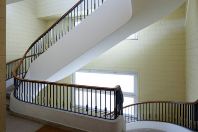 Immagine di una scala curva design con pedata in cemento e alzata in marmo
