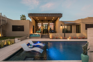 This is an example of a large contemporary backyard rectangular pool in Phoenix with natural stone pavers.