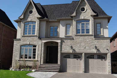 Photo of a large traditional two-storey beige house exterior in Toronto with mixed siding.
