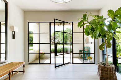Design ideas for a beach style foyer in Dallas with grey walls, a pivot front door, a glass front door and grey floor.