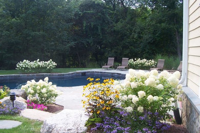 This is an example of a mid-sized traditional backyard full sun garden in New York with natural stone pavers.