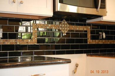 Example of a mid-sized classic u-shaped ceramic tile kitchen pantry design in Orange County with a double-bowl sink, shaker cabinets, white cabinets, granite countertops, black backsplash, glass tile backsplash, stainless steel appliances and no island