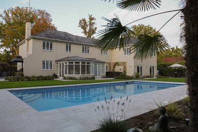 This is an example of a large modern backyard rectangular pool in Surrey with tile.