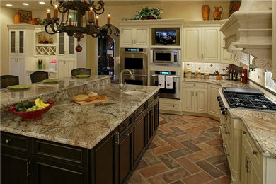 Eat-in kitchen - mid-sized mediterranean l-shaped porcelain tile and brown floor eat-in kitchen idea in Chicago with a farmhouse sink, beaded inset cabinets, white cabinets, granite countertops, beige backsplash, porcelain backsplash, stainless steel appliances and an island