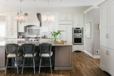 This is an example of a large traditional l-shaped open plan kitchen in Atlanta with a farmhouse sink, stainless steel appliances, with island, brown floor, flat-panel cabinets, grey cabinets, granite benchtops, multi-coloured splashback, glass tile splashback, medium hardwood floors and beige benchtop.