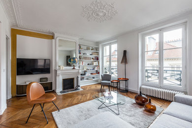 Inspiration pour un salon traditionnel de taille moyenne et ouvert avec un mur blanc, un sol en bois brun, une cheminée standard, un téléviseur encastré, une bibliothèque ou un coin lecture, un manteau de cheminée en béton et éclairage.