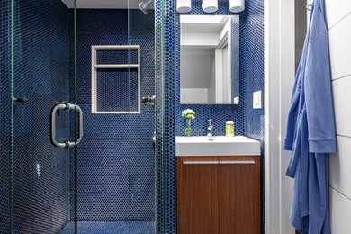 Mid-sized contemporary 3/4 bathroom in New York with flat-panel cabinets, medium wood cabinets, an alcove shower, blue tile, mosaic tile, an integrated sink, grey floor, a hinged shower door and white benchtops.