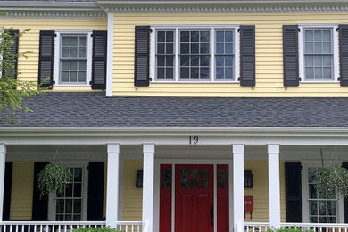 Inspiration for a large timeless yellow two-story concrete fiberboard house exterior remodel in Boston with a hip roof, a shingle roof and a black roof