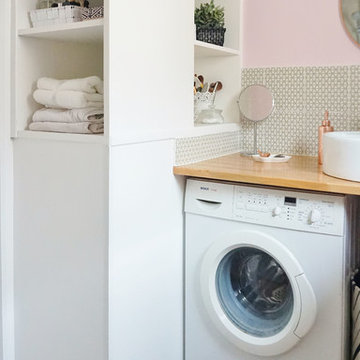 Une petite salle d'eau rose et une petite cuisine grise dans un immeuble ancien