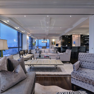 Inredning av ett modernt stort allrum med öppen planlösning, med en hemmabar, vita väggar, mörkt trägolv och en inbyggd mediavägg