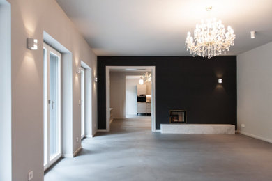 Großes, Offenes Modernes Wohnzimmer mit weißer Wandfarbe, Betonboden, Tunnelkamin, Kaminumrandung aus Stein, grauem Boden und Holzwänden in Berlin