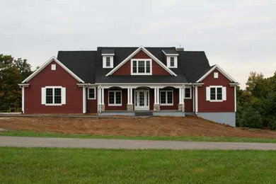 Inspiration for a large farmhouse red two-story wood exterior home remodel in Other with a shingle roof