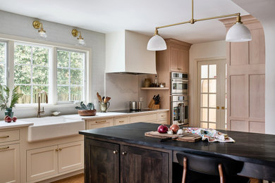 Cette photo montre une cuisine américaine chic de taille moyenne avec une crédence blanche, un sol en bois brun et un plan de travail blanc.