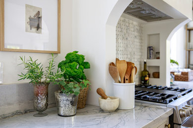 Example of a mid-sized transitional l-shaped light wood floor and brown floor open concept kitchen design in Cincinnati with a farmhouse sink, shaker cabinets, beige cabinets, quartzite countertops, gray backsplash, stone slab backsplash, paneled appliances, an island and gray countertops