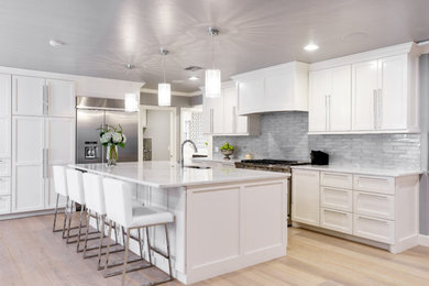 Inredning av ett klassiskt vit vitt kök, med skåp i shakerstil, vita skåp, blått stänkskydd, stänkskydd i glaskakel, en köksö och vitt golv