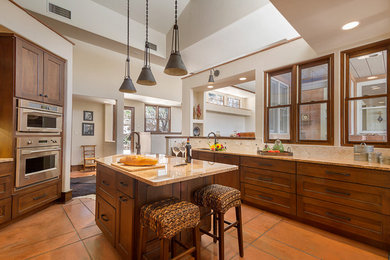 Enclosed kitchen - southwestern galley terra-cotta tile enclosed kitchen idea in Phoenix with an undermount sink, flat-panel cabinets, dark wood cabinets, granite countertops, white backsplash, stone tile backsplash, paneled appliances and an island