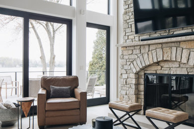 Example of a large mountain style open concept porcelain tile and gray floor living room design in Grand Rapids with white walls, a standard fireplace, a stone fireplace and a wall-mounted tv