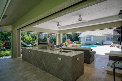 Patio kitchen - large tropical backyard stone patio kitchen idea in Miami with a roof extension
