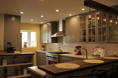Example of a large arts and crafts l-shaped dark wood floor eat-in kitchen design in San Francisco with a farmhouse sink, raised-panel cabinets, gray cabinets, quartz countertops, white backsplash, subway tile backsplash, stainless steel appliances and a peninsula