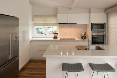Design ideas for a mid-sized contemporary l-shaped eat-in kitchen in Melbourne with a double-bowl sink, flat-panel cabinets, white cabinets, quartz benchtops, beige splashback, ceramic splashback, stainless steel appliances, medium hardwood floors and with island.