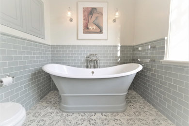 Inspiration for a large classic ensuite bathroom in Devon with a freestanding bath, an alcove shower, a wall mounted toilet, green tiles, metro tiles, ceramic flooring, a wall-mounted sink, multi-coloured floors and a sliding door.