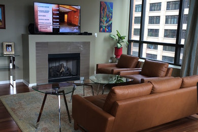 Inspiration for a mid-sized modern loft-style medium tone wood floor and brown floor living room remodel in Chicago with green walls, a standard fireplace, a tile fireplace and a wall-mounted tv