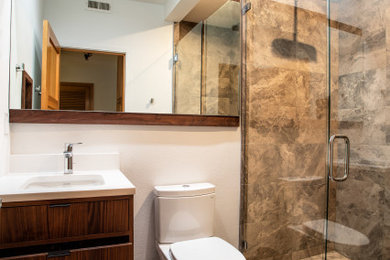 Example of a mid-sized minimalist 3/4 brown tile and ceramic tile ceramic tile and gray floor double shower design in Portland with flat-panel cabinets, dark wood cabinets, a two-piece toilet, white walls, an undermount sink, quartz countertops, a hinged shower door and white countertops