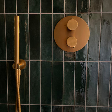 Gold Lusso Stone shower controls with green porcelain tiles