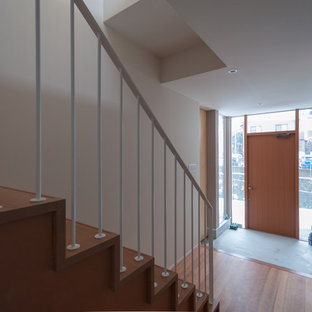 Выдающиеся фото от архитекторов и дизайнеров интерьера: узкая прихожая в стиле модернизм с белыми стенами, полом из фанеры и входной дверью из дерева среднего тона