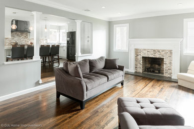 Inspiration for a large transitional open concept medium tone wood floor and brown floor living room remodel in New York with gray walls, a standard fireplace, a stone fireplace and a wall-mounted tv
