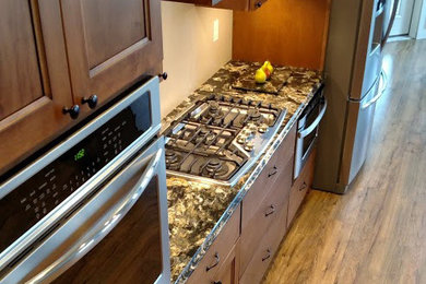 Inspiration for a transitional l-shaped medium tone wood floor kitchen pantry remodel in Minneapolis with recessed-panel cabinets, medium tone wood cabinets, granite countertops, stainless steel appliances and a peninsula