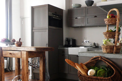 This is an example of a large contemporary u-shaped eat-in kitchen in Paris with a farmhouse sink, distressed cabinets, panelled appliances, dark hardwood floors, with island and grey splashback.