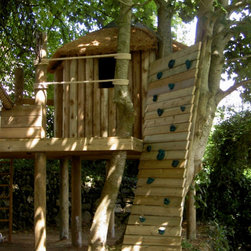 Curved climbing wall ascending up into the canopy towards a woodland treehouse e - Garden Playhouses