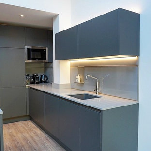 Mid-sized contemporary kitchen pantry designs - Mid-sized trendy u-shaped kitchen pantry photo in Hertfordshire with gray cabinets, quartzite countertops, gray backsplash, glass sheet backsplash, an island, white countertops and flat-panel cabinets