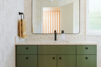 Inspiration for a mid-sized mid-century modern medium tone wood floor and wallpaper powder room remodel in Portland with flat-panel cabinets, green cabinets, white walls, an undermount sink, quartz countertops, multicolored countertops and a built-in vanity