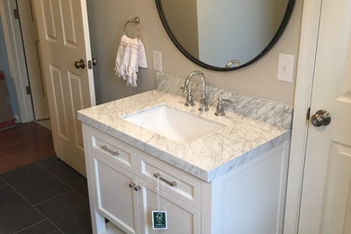 Example of a mid-sized classic 3/4 porcelain tile and gray tile porcelain tile and black floor bathroom design in Other with shaker cabinets, white cabinets, white walls, an undermount sink, marble countertops and a two-piece toilet