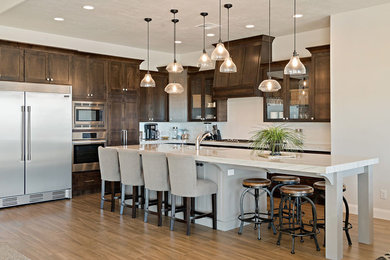 Open concept kitchen - large contemporary l-shaped ceramic tile and brown floor open concept kitchen idea in Salt Lake City with a single-bowl sink, shaker cabinets, brown cabinets, quartzite countertops, white backsplash, ceramic backsplash, stainless steel appliances, an island and white countertops
