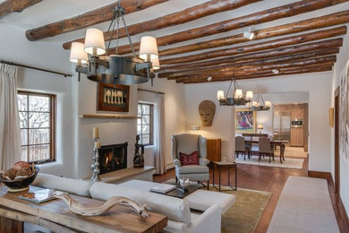 Example of a large southwest formal and open concept medium tone wood floor living room design in Albuquerque with white walls, a standard fireplace, a plaster fireplace and no tv