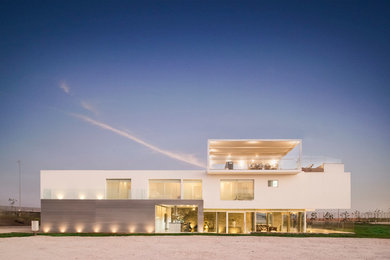 Large trendy white three-story mixed siding flat roof photo in Other