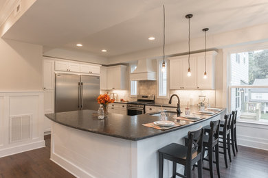 Open concept kitchen - mid-sized modern u-shaped dark wood floor and brown floor open concept kitchen idea in Other with an undermount sink, shaker cabinets, white cabinets, quartz countertops, white backsplash, stone tile backsplash, stainless steel appliances and black countertops