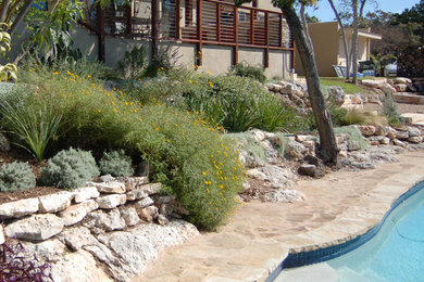 Inspiration for a large rustic drought-tolerant and full sun backyard stone retaining wall landscape in Austin.