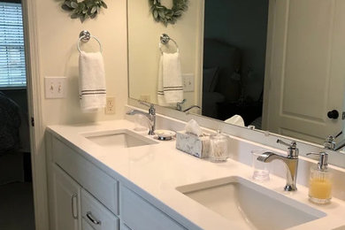 Modelo de cuarto de baño principal y doble de tamaño medio con armarios con paneles con relieve, puertas de armario blancas, lavabo bajoencimera, encimera de cuarzo compacto y encimeras blancas