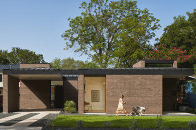 Пример оригинального дизайна: одноэтажный, кирпичный, коричневый частный загородный дом в стиле модернизм с вальмовой крышей, металлической крышей и черной крышей