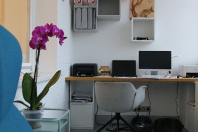 На фото: рабочее место среднего размера в современном стиле с белыми стенами, полом из керамогранита, отдельно стоящим рабочим столом, серым полом и кирпичными стенами с