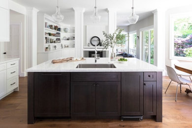 Open concept kitchen - large contemporary medium tone wood floor and beige floor open concept kitchen idea in San Francisco with an undermount sink, shaker cabinets, brown cabinets, quartz countertops, white backsplash, ceramic backsplash, paneled appliances, an island and white countertops