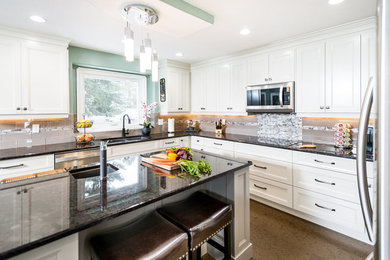 Example of a large trendy u-shaped brown floor kitchen design in Calgary with a double-bowl sink, recessed-panel cabinets, white cabinets, granite countertops, brown backsplash, subway tile backsplash, stainless steel appliances and an island