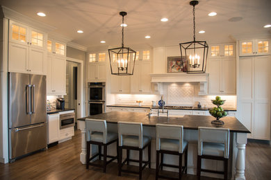Open concept kitchen - large transitional l-shaped medium tone wood floor and gray floor open concept kitchen idea in Cincinnati with a farmhouse sink, flat-panel cabinets, white cabinets, soapstone countertops, white backsplash, subway tile backsplash, stainless steel appliances and an island