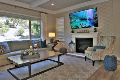 Example of a large beach style open concept porcelain tile, brown floor, exposed beam and wallpaper living room design in Orange County with gray walls, a standard fireplace, a wood fireplace surround and a wall-mounted tv