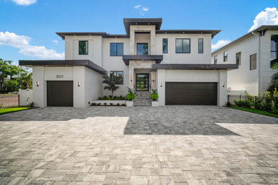 Large modern white two-story stucco exterior home idea in Tampa with a shingle roof and a brown roof